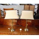 A pair of modern swing arm metal table lamps with cream shades