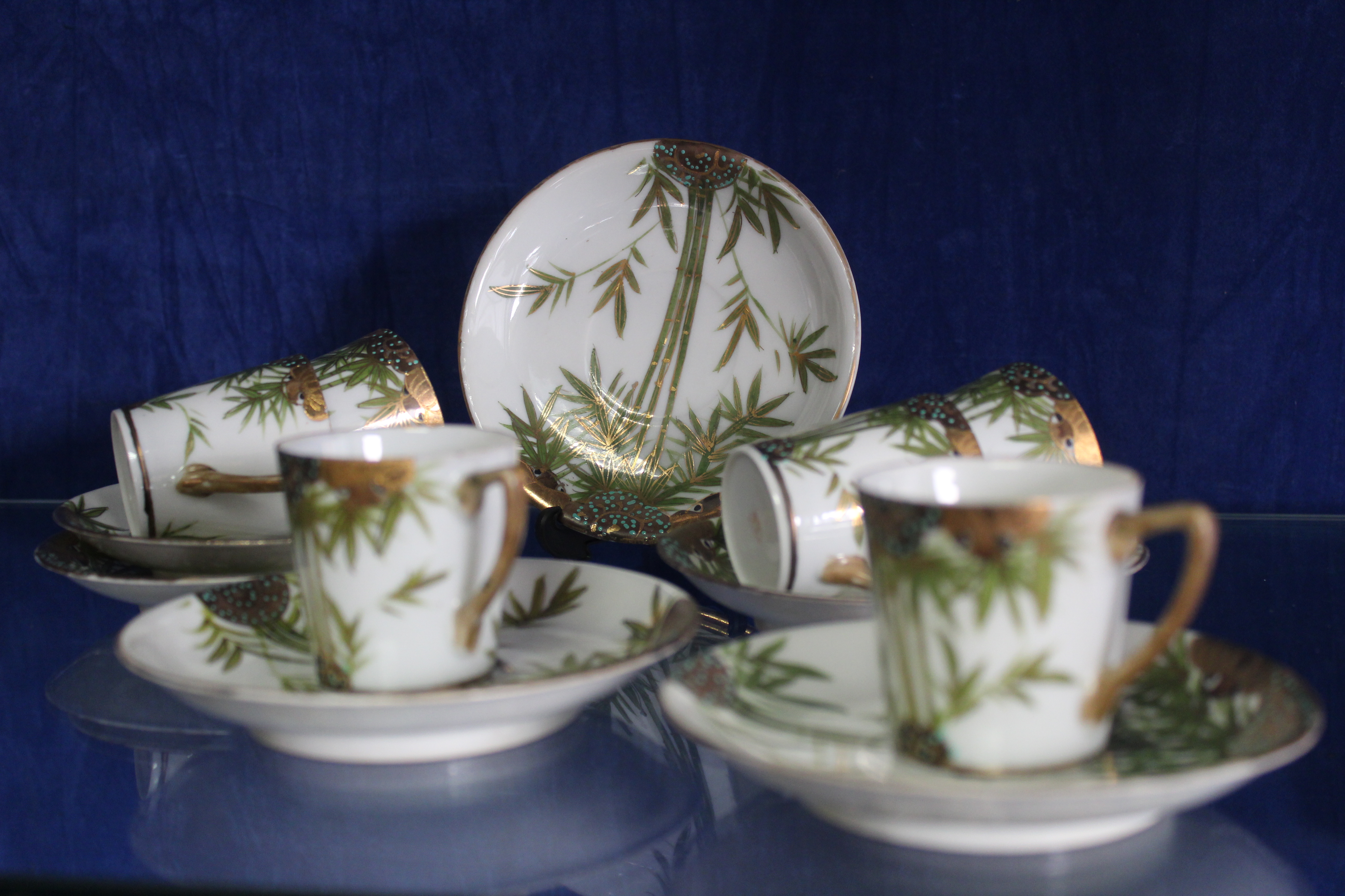 An oriental eggshell porcelain set of six coffee cups and saucers, hand painted with bamboo design