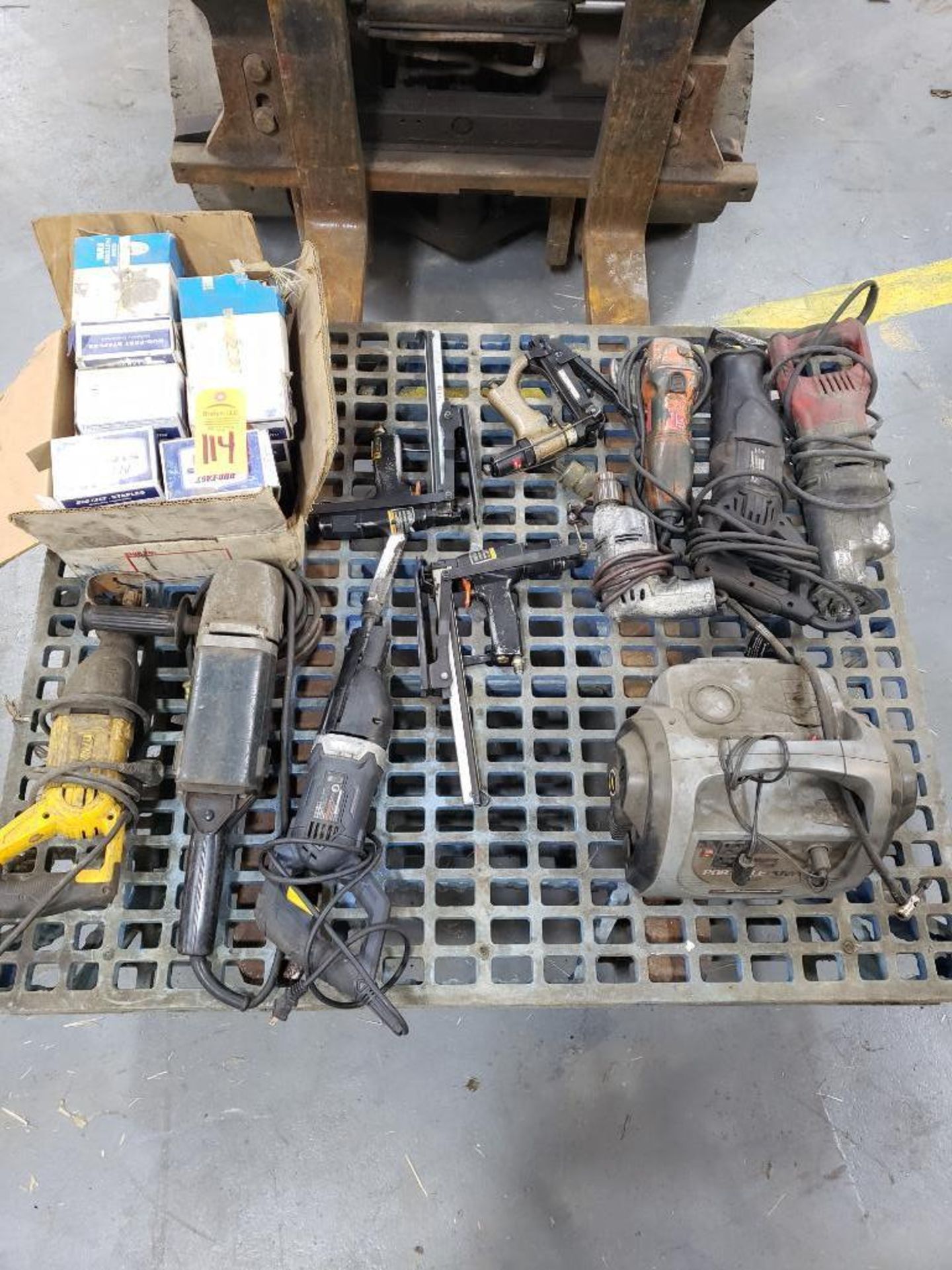 Pallet of assorted power tools, staple guns, box of staples, and charger.