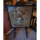 A William IV Rosewood Firescreen, With a floral decorated tapestry panel, raised on scroll