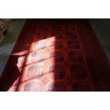 A Machine Made Afghan Rug, Decorated with six rows of three geometric medallions on a red ground,