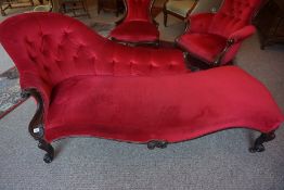 A Victorian Mahogany Chaise Longue, Upholstered in later red button back velour, Raised on scroll