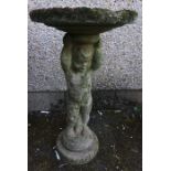 A Stone Garden Plant Stand, Modelled as a Putti style child holding aloft the circular stand, 80cm