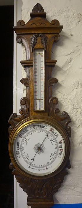 An Edwardian Carved Oak Wheel Barometer, Having a thermometer gauge above enamel dial, 88cm high