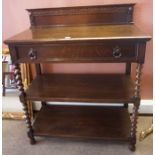 An Oak Serving Table, Having a single drawer above two open tiers, raised on barley twist columns,