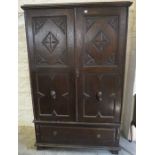 A Jacobean Style Oak Wardrobe, Having two carved doors enclosing a hanging rail, above a large
