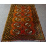 An Afghan Rug, Hand knotted, Decorated to the centre with six rows of two geometric medallions on an