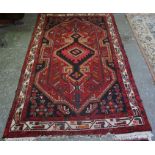 A Persian Rug, Decorated with geometric medallion and motifs, on a red ground, 220cm x 140cm