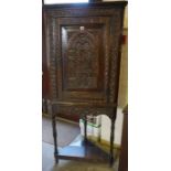 A Jacobean Revival Carved Oak Corner Cabinet, Having a cupboard door enclosing a shelved interior,