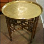 An Indian Style Brass Top Table, raised on folding supports, 58cm high, 53cm wide