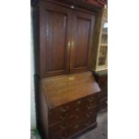 A George III Oak Bureau Bookcase, Having two doors, enclosing a shelved interior, above a fall front