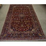 A Kashan Rug, Decorated with allover floral medallions and swags, on a red ground with aubergine