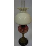 A Vintage Brass Corinthian Style Oil Lamp, Having a cranberry glass reservoir, with shade, 40cm