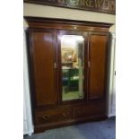 A Mahogany Wardrobe, Having a mirrored door, flanked with a panelled door, above two drawers,