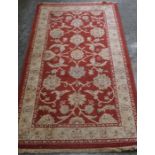 A Small Persian Style Rug, Decorated with floral swags on a red ground, with cream border, 161cm x