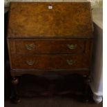 A Walnut Writing Bureau, Having a fall front, enclosing pigeon holes, above two long drawers,