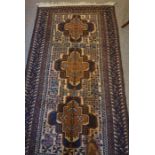 An Afghan Bluch Rug, Having three large geometric medallions to the centre, on a brown ground, 200cm