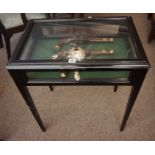 An Ebonised Shop Bijouterie Cabinet, Having a hinged glazed top, also with glazed panels, raised