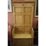 A Pine Hall Settle, Having later coat hooks to the top, above a hinged seat, 193cm high, 89cm