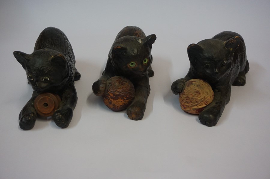 Three Similar Bretby Terracotta Cat figures, each figure having glass eyes and holding a ball,