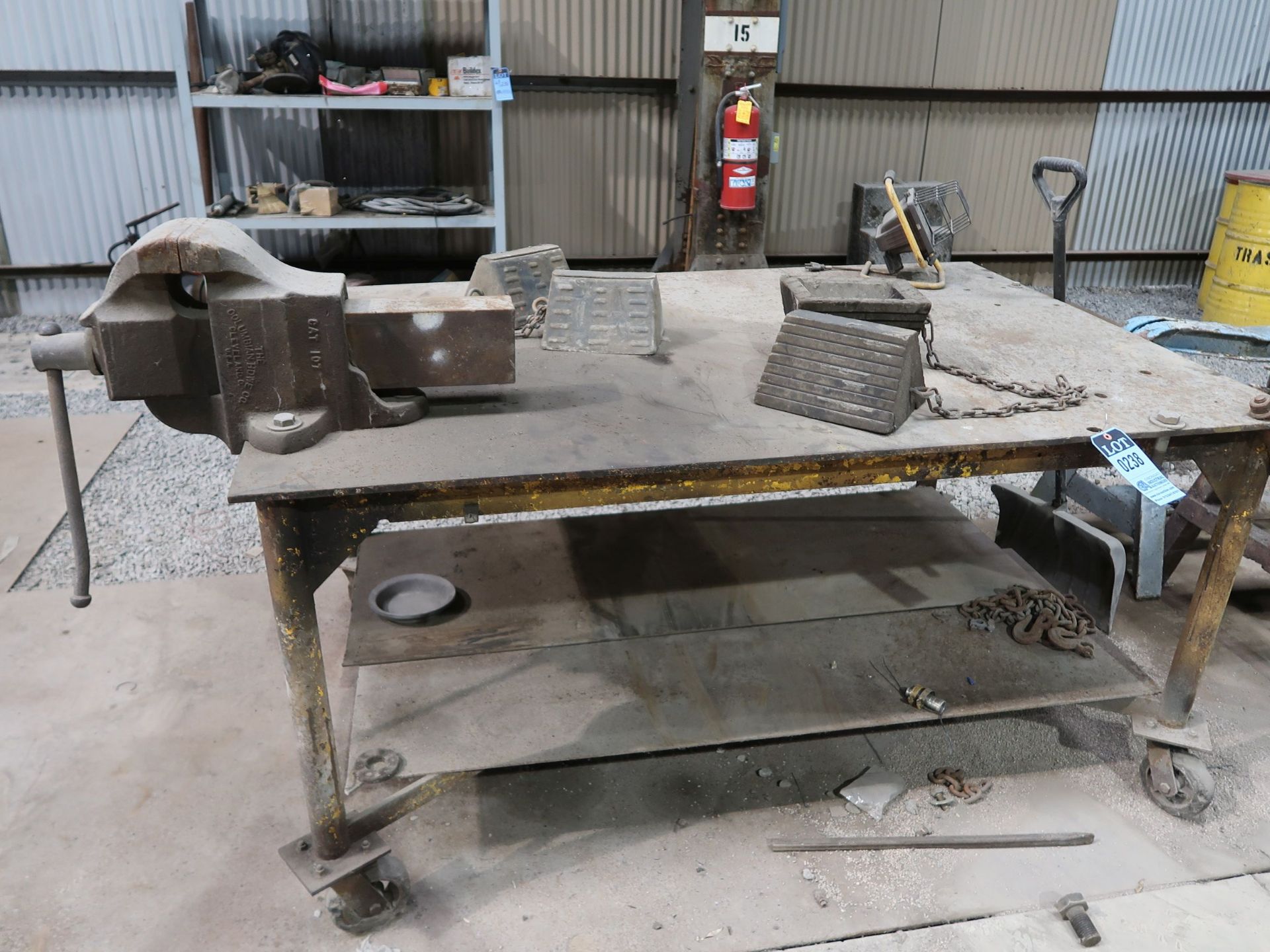 (LOT) STEEL TABLE WITH 6" BENCH VISE, (2) STEEL SAW HORSES, TRUCK TIRE CHUCKS, STEEL SHELF