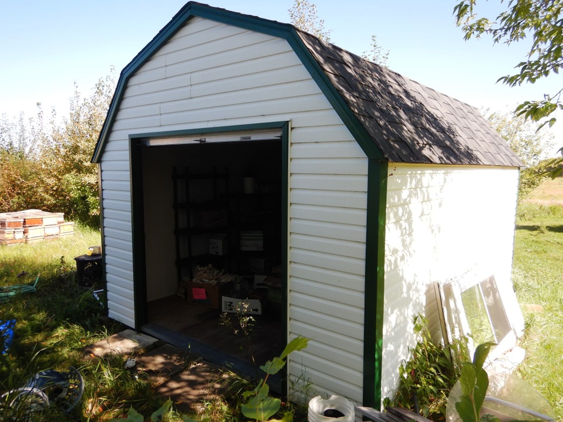 12'X16' SKIDDED HIP ROOF VINYL CLAD BUILDING W/ 7'X7' ROLL UP METAL DOOR, PARTIALLY INSULATED &