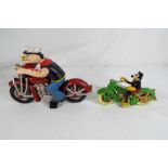 A cast iron novelty figure of Mickey Mouse and Popeye riding motorcycles.