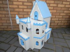A wooden dolls house with accessories in the form of a castle, approximately 70 cm x 59 cm x 30 cm.