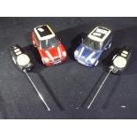 Two Mini Cooper remote control cars with remote controls and aerials.