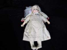 A ceramic headed doll marked to the rear with the number 8 with glass sleeping eyes,