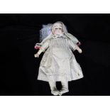 A ceramic headed doll marked to the rear with the number 8 with glass sleeping eyes,