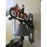 A cast iron wall hanging bell with motorbike shaped top