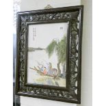 A modern Chinese porcelain panel in caved dark wood frame Good condition overall.