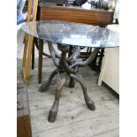 A circular glass topped table on folding wooden base