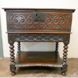 An antique oak bible box with carved decoration and under tier standing on barley twist legs,