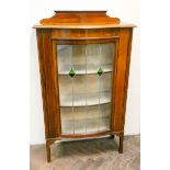 An Edwardian mahogany bow front display cabinet with lead lined doors and painted decoration,