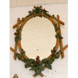 An oval wall mirror in rustic painted wood and leaf frame