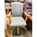 Revolving office elbow chair with green upholstered seat and back