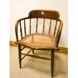 A tub shaped oak spindle back elbow chair with cane seat