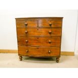 A mahogany bow front chest of three long and two short drawers with bun handles standing on turned