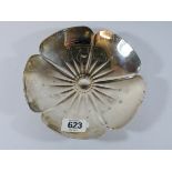 A silver flower shaped dish standing on ball feet,