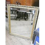 A large bevelled wall mirror in decorative gilt frame