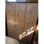 A modern pine three door wardrobe with four drawers under 4'6 wide