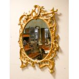 A Victorian style decorative oval gilt framed wall mirror in carved wooden frame