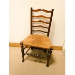 An antique oak ladder back dining chair with rush seat