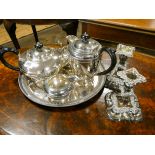 A four piece plated tea set on circular tray and a pair of plated candlesticks