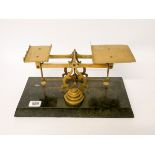 A set of brass scales and weights mounted on a heavy marble base,