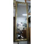 A long bevelled wall mirror in decorative gilt frame