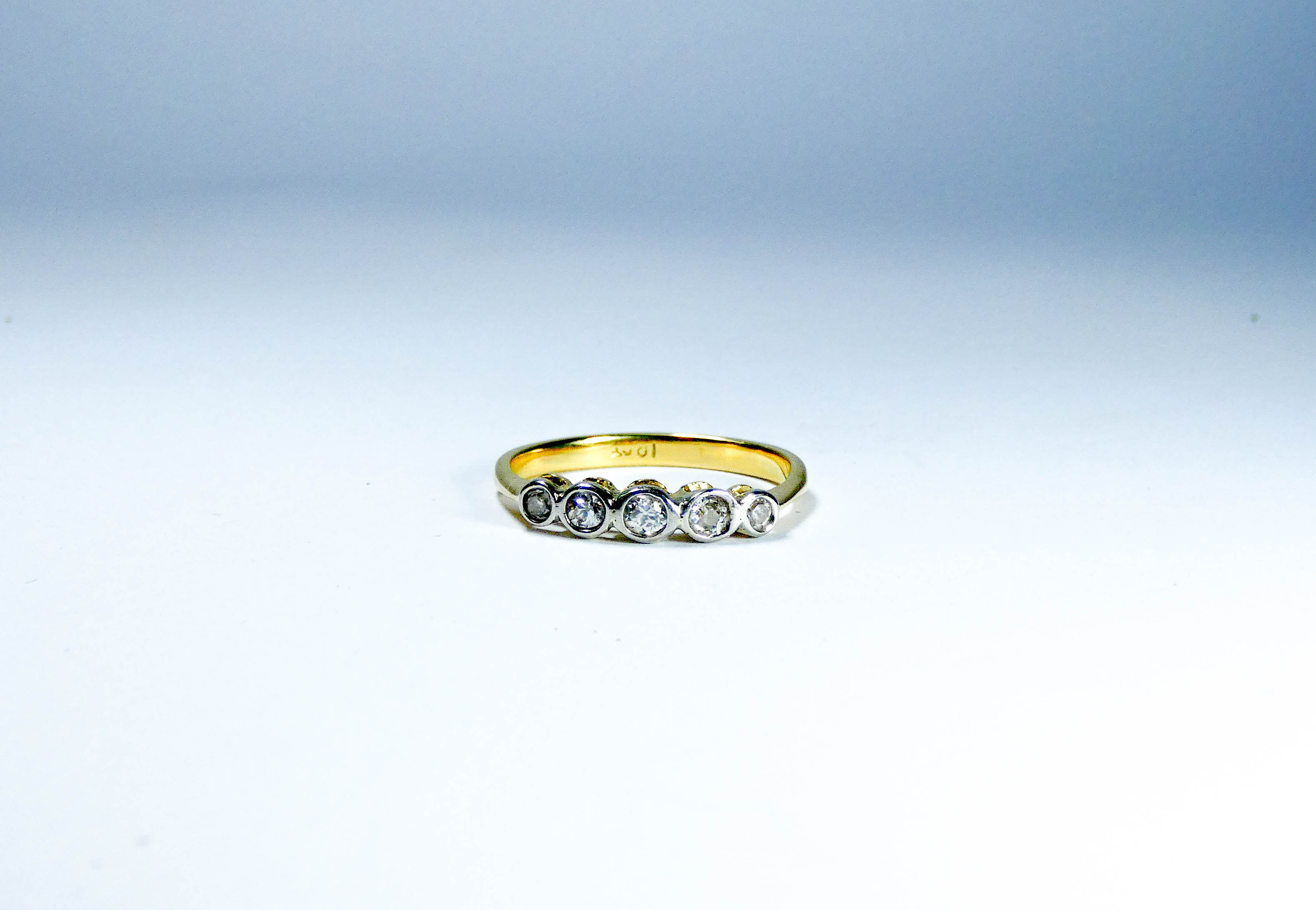 A five stone diamond ring set with brilliant cut diamonds in a rub over setting,