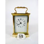 A brass carriage clock in its original red maroon leather carrying case,